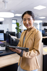 Vertical image of happy asian businesswoman looking at camera in office