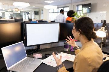 Asian woman sitting at desk and having video call on computer with copy space in office