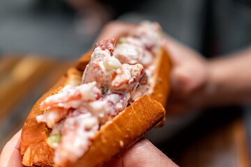 Maine lobster roll sandwich in brioche bun bread macro closeup texture in seafood restaurant cafe...