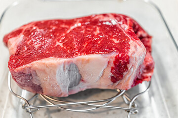 Macro closeup of New York boneless strip steak beef thick cut meat in glass pan for roasting before...