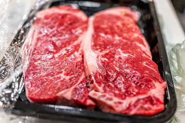 Two raw red strip steaks cuts of meat closeup macro of texture butcher cut on plastic tray in kitchen