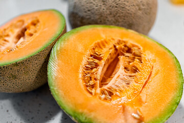 Colorful orange cantaloupe melon cut in half with halves macro closeup and seeds of juicy fruit and...