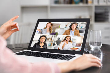 Woman talking with female co-workers via video call at home.
