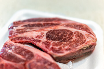 Lamb shoulder blade chops package from butcher on plastic tray with texture closeup of bone and...