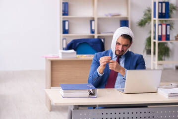 Young male employee suffering from toothache at workplace