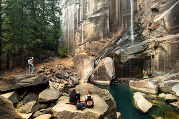 A couple have a picnic in front of Vernal Falls while a man takes a photo at the waterfall, Yosemite NP
