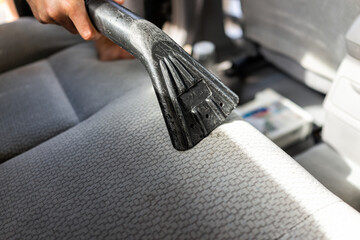 Vacuum cleaner at car wash station, man cleaning vehicle back rear seat upholstery at inside...