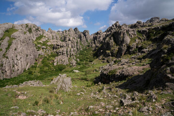 Panoramic view of the rock massif Los Gigantes in Cordoba, Argentina, under a blue sky with clouds.