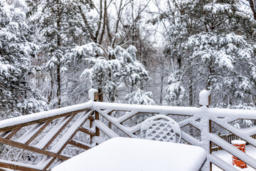 White snow covered metal outdoor table chair closeup on home house wooden deck with railing fence...