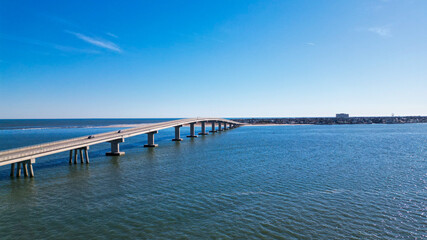 Fototapeta premium Aerial drone view of a smooth long bridge over a dark blue body of water