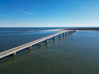 Fototapeta na wymiar Aerial drone view of a smooth long bridge over a dark blue body of water