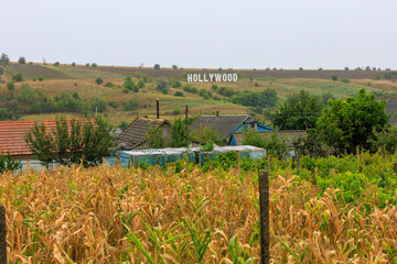 Hollywood inscription on green hill in cloudy weather
