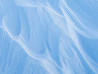 Snow texture. Wind sculpted patterns on snow surface. Wind in the tundra and in the mountains on the surface of the snow sculpts patterns and ridges (sastrugi). Arctic, Polar region. Winter background
