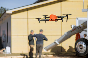 As employees pour concrete near newly constructed home on construction site with help of drone an...