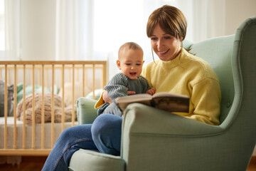 Obraz premium Mother reading a book to her baby boy