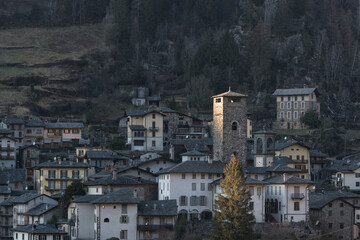 Little village of Gromo, Lombardy, Italy - February 2023. The last rays of the setting sun illuminate the village