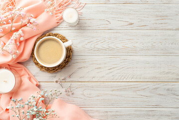 Hello spring concept. Top view photo of cup of coffee on rattan serving mat candles gypsophila flowers and pink scarf on grey wooden desk background with copyspace