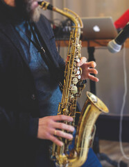 Fototapeta premium Concert view of saxophonist, a saxophone sax player with vocalist and musical band during jazz orchestra show performing music on stage in the scene lights