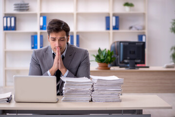 Naklejka premium Young male employee and too much work in the office