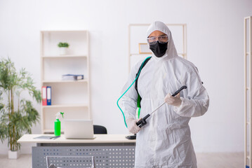 Young male contractor disinfecting office during pandemic