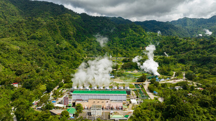Aerial view of geotermal power plant in the mountains. Geothermal station with steam and pipes....