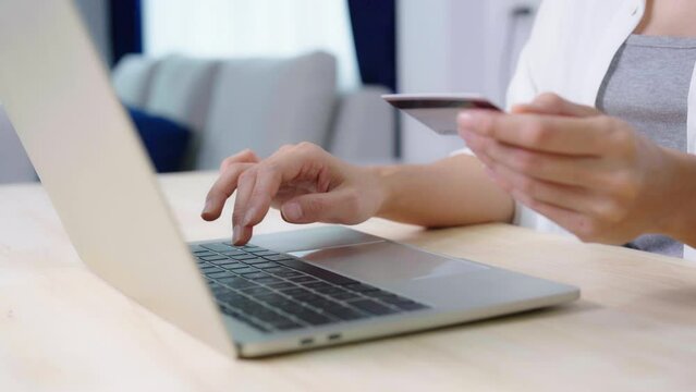 Young asian woman makes online banking payments through the internet from bank card on computer laptop. Shopping online on notebook with credit card