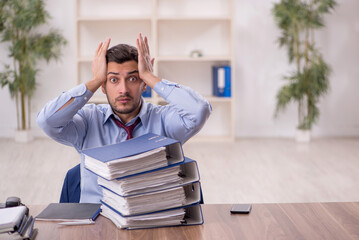 Young male employee and too much work in the office