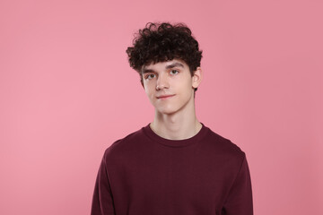 Portrait of cute teenage boy on pink background