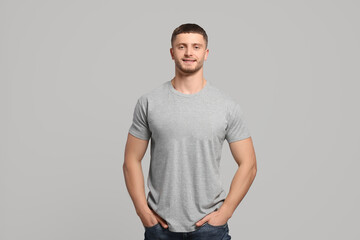 Man wearing blank t-shirt on light grey background. Mockup for design