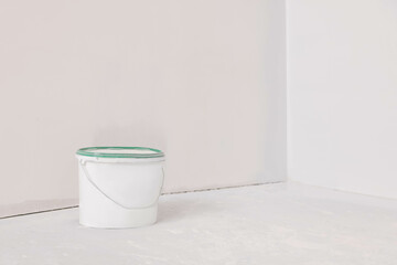 Bucket with paint in empty room, space for text