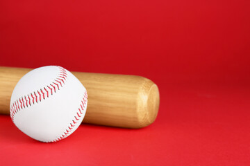 Wooden baseball bat and ball on red background, closeup. Space for text