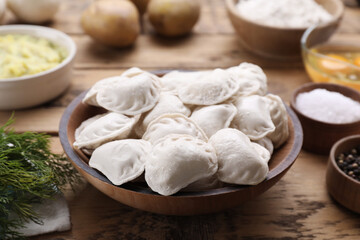 Fototapeta na wymiar Raw dumplings (varenyky) and ingredients on wooden table, closeup