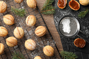 Fototapeta na wymiar Homemade walnut shaped cookies with boiled condensed milk and fir branches on wooden table, flat lay