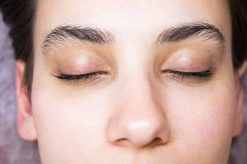 Woman lying on the couch after eyelash lamination procedure. 