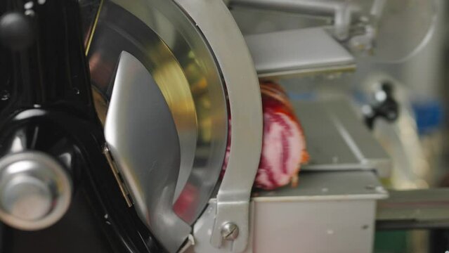 Capocollo being sliced at an Italian deli. Fresh deli meat being sliced on a meat slicer.