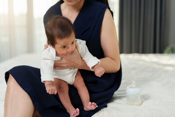 mother holding newborn baby burping in bedroom after feeding milk