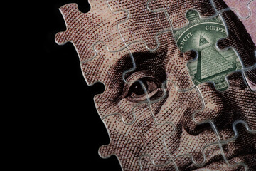 Jigsaw puzzle with a portrait of Benjamin Franklin from a 100 US dollar bill and a fragment of a 1...