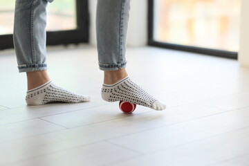 Female leg in socks on the massage ball on the floor