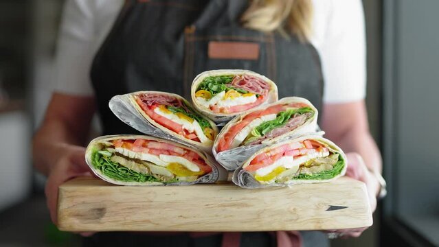 Chef holding a pile of deli sandwiches on a platter. Catering platter of Italian deli sandwiches. chef preparing many Italian sandwiches at a deli restaurant.