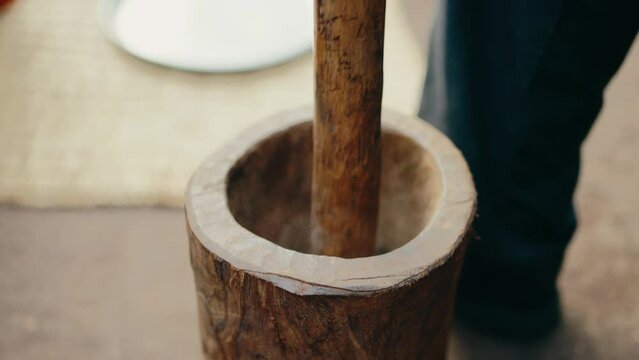 Close-up view of wooden mortar and pestle used to manually grind coffee beans