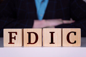 The word "FDIC" written on wood cube.