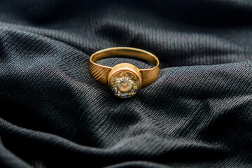 Gold ring with zircon stones placed on black velvet cloth