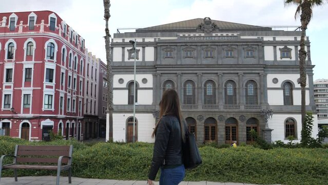 woman walks admiring the Benito Perez Galdos theater in Las Palmas de Gran Canaria and on a sunny day.