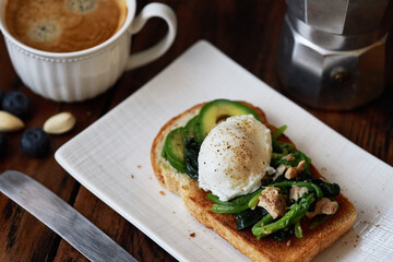 homemade healthy open sandwich: toast topped with spinach, tuna, avocado and poached egg