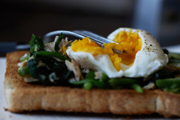 homemade healthy open sandwich: toast topped with spinach, tuna, avocado and poached egg