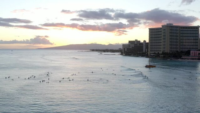 Aerial pull out view as droves of surfers enjoy the sunset over Waikiki Beach in Hawaii.