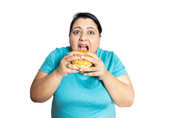 Overweight asian woman eating burger isolated over white background,studio portrait.Plus size female enjoy fast food. Copy space.