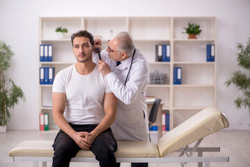 Fototapeta premium Young male doctor visiting old doctor otolaryngologist