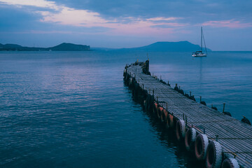 Fototapeta premium Old wooden fishing pier goes into the sea on sunset. Resort city Novyi Svet, Crimea