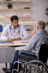 Fototapeta premium Old man in wheelchair visiting young male doctor